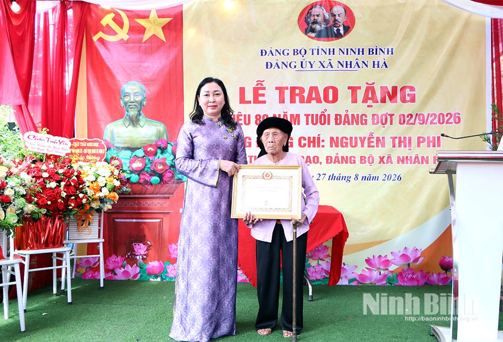 Đồng chí Đinh Thị Lụa, Phó Bí thư Tỉnh uỷ, Chủ tịch Uỷ ban MTTQ Việt Nam tỉnh trao tặng Huy hiệu 80 năm tuổi Đảng cho đồng chí Nguyễn Thị Phi, Chi bộ thôn Do Đạo, Đảng bộ xã Nhân Hà.